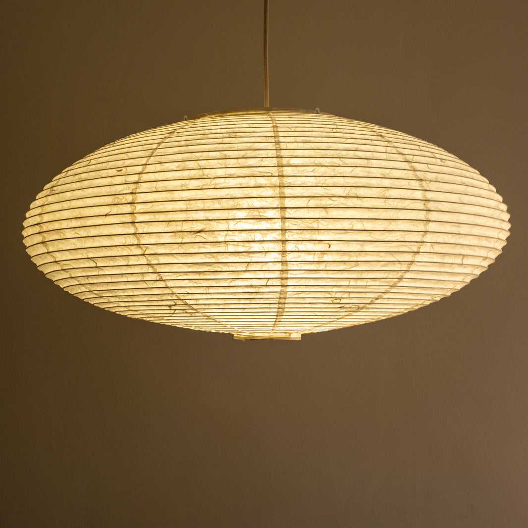 An elliptical-shaped Japanese paper lampshade from white Unryu paper, straight view, lit.