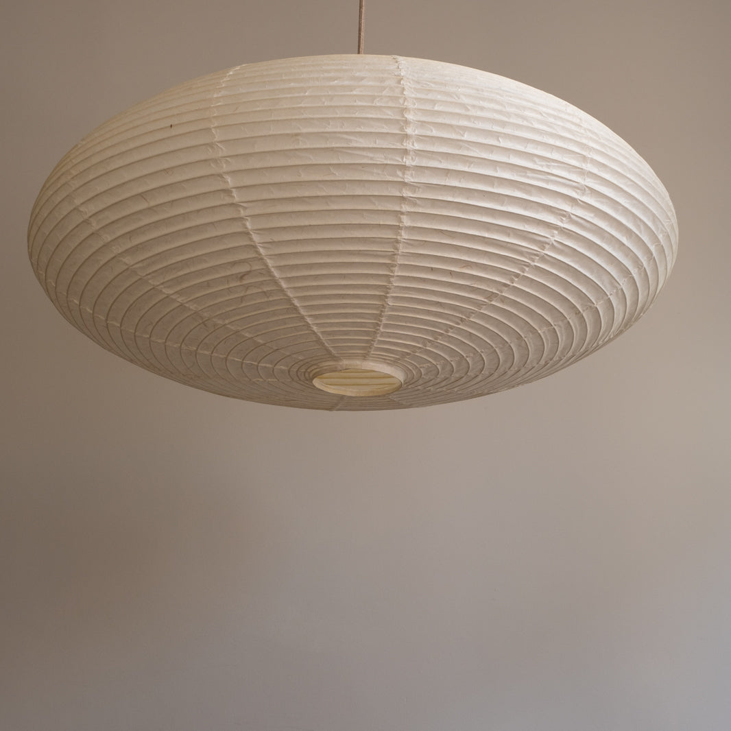 An elliptical-shaped Japanese paper lampshade from white Unryu paper, pictured from beneath, unlit.