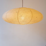 A lit elliptical 90cm Japanese paper lampshade, made from warm organic natural kozo washi paper