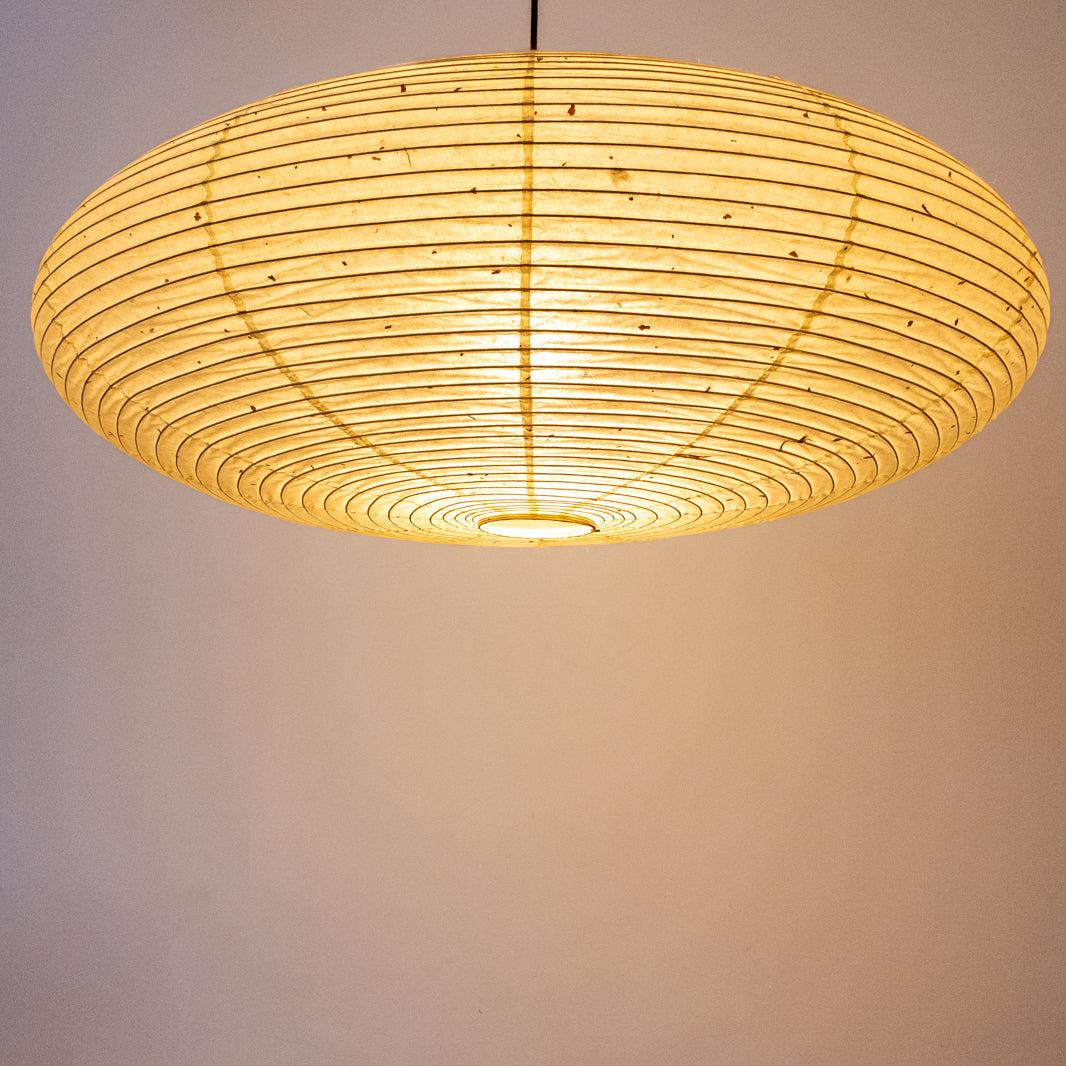 A lit elliptical 90cm Japanese paper lampshade, made from warm organic natural kozo washi paper, underneath view