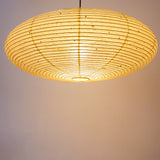 A lit elliptical 90cm Japanese paper lampshade, made from warm organic natural kozo washi paper, underneath view