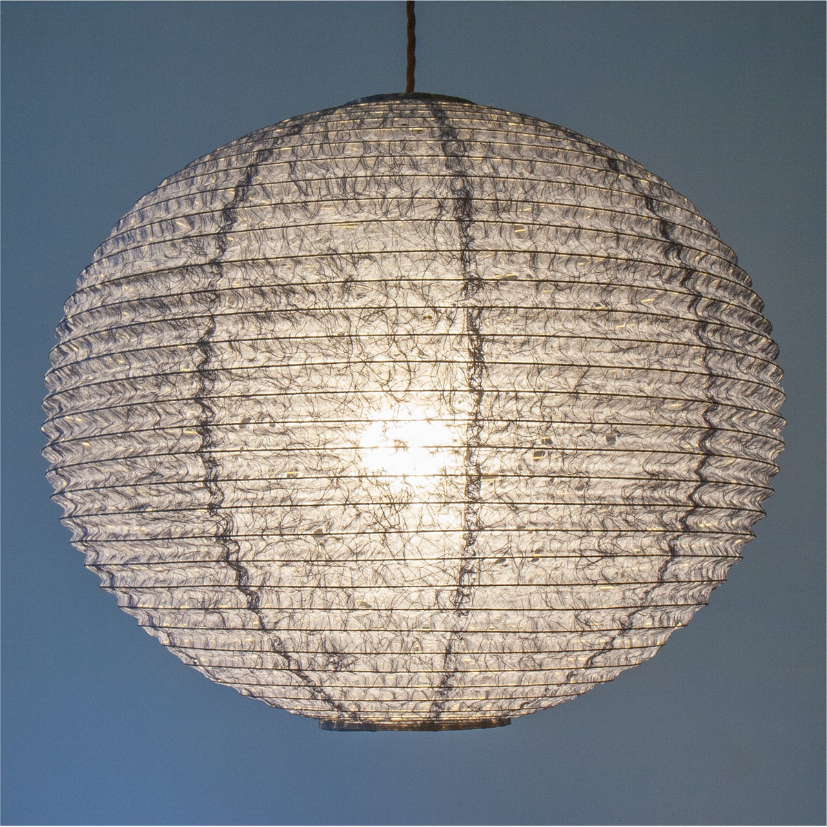 A 53cm navy blue hemp washi paper lamp shade with small holes, casting a soft light