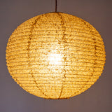 A large 53cm green/brown hemp washi paper lamp shade with small holes, hanging and casting a warm light.