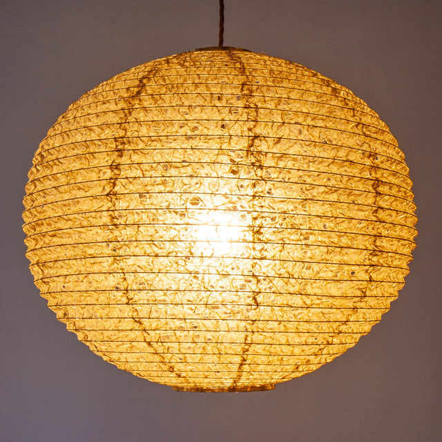 A large 53cm green/brown hemp washi paper lamp shade with small holes, hanging and casting a warm light.