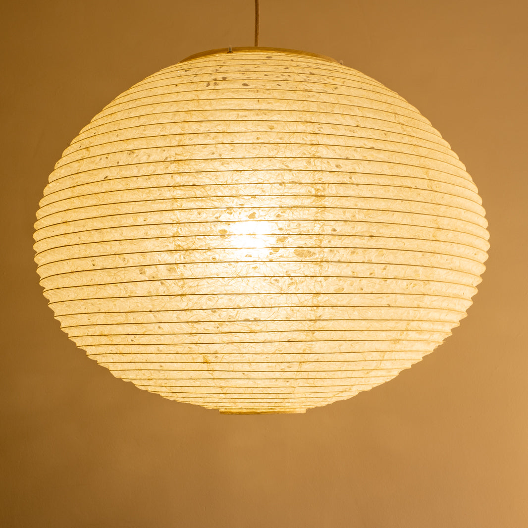 A large 71cm maru (round) paper lampshade, handmade from Japanese hemp washi paper in the asaraku style, where small holes are left in the paper, illuminated