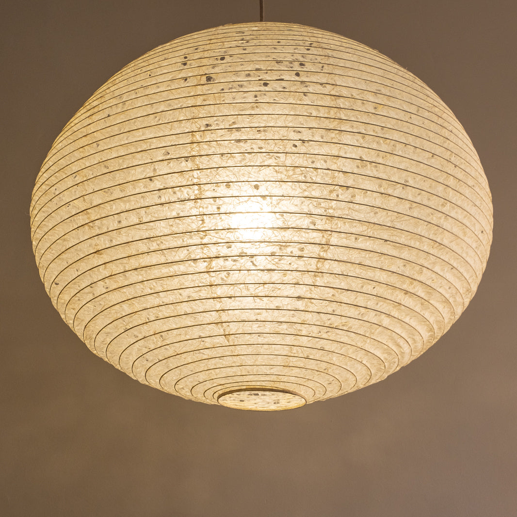 A large 71cm maru (round) paper lampshade, handmade from Japanese hemp washi paper in the asaraku style, where small holes are left in the paper, under view, illuminated