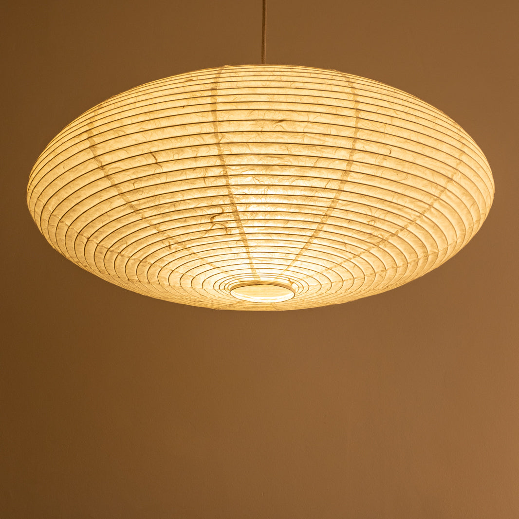 An elliptical-shaped Japanese paper lampshade from white Unryu paper, pictured from beneath, lit.