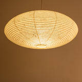 An elliptical-shaped Japanese paper lampshade from white Unryu paper, pictured from beneath, lit.