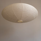 An elliptical-shaped Japanese paper lampshade from white Unryu paper, pictured from beneath, unlit.