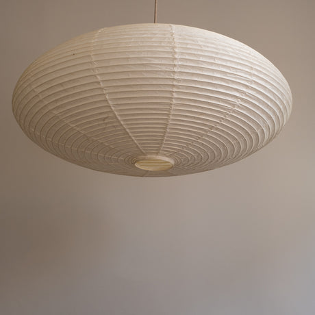 An elliptical-shaped Japanese paper lampshade from white Unryu paper, pictured from beneath, unlit.