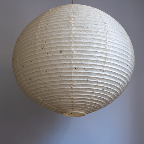 A 71cm, round, handmade kozo washi paper lamp shade with natural flecks, unilluminated.